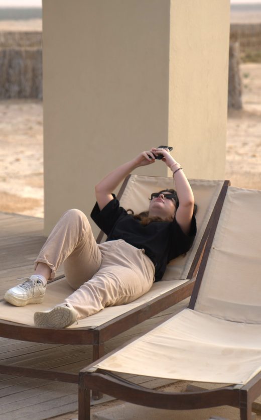 A teammate lounging on a sunbed, taking a photo with a phone
