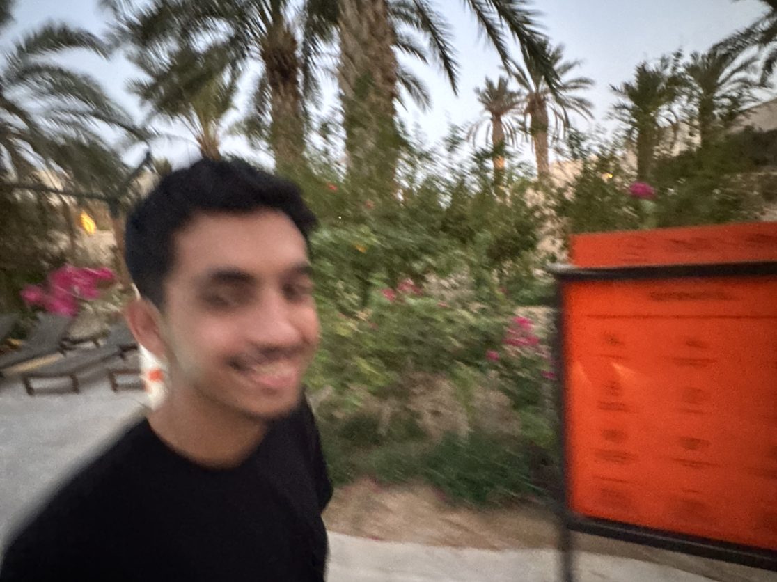 A smiling, motion-blurred selfie under palm trees