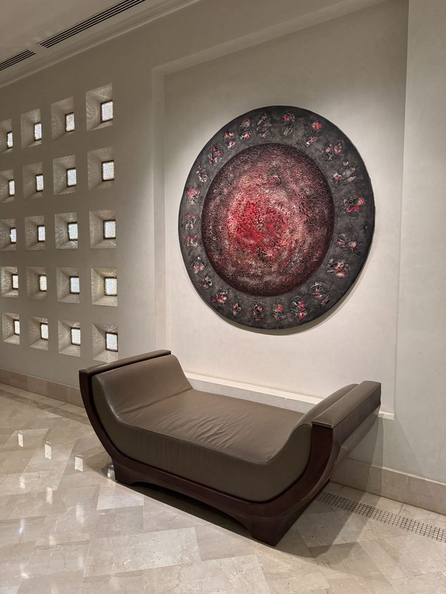 A hotel corridor with a bench under a round artwork